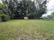 Large, grassy backyard with mature trees, shed, and volleyball net at 108 Country Club Cir, Sanford, FL 32771
