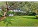 Spacious backyard with lush green grass, mature trees, a privacy fence, and charming egg swing chairs at 11425 Claymont Cir, Windermere, FL 34786
