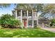 Classic two-story home boasts stately pillars, a well-manicured lawn, an orange front door, and mature landscaping at 11425 Claymont Cir, Windermere, FL 34786