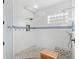 Large tiled shower with stone floor, glass block window, and shower bench at 11425 Claymont Cir, Windermere, FL 34786