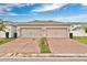 Two-car garage with a brick paved driveway and manicured landscaping enhance the home's curb appeal at 12015 Prologue Ave, Orlando, FL 32832