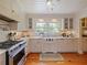 Bright kitchen features white cabinetry, stainless steel appliances, farmhouse sink, and hardwood floors at 1227 Golden Ln, Orlando, FL 32804