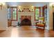 Charming living room featuring a brick fireplace, hardwood floors, and natural light from large windows at 1227 Golden Ln, Orlando, FL 32804