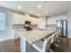 This kitchen showcases a large island with seating, white cabinets, quartz countertops, and stainless steel appliances at 1540 Orange Valley Rdg, Ocoee, FL 34761
