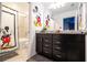 Fun bathroom featuring a Mickey Mouse theme, vanity with granite countertop, and shower/tub combo at 16061 Blue Wave Way, Clermont, FL 34714