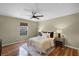 Well-lit bedroom featuring a dark ceiling fan, neutral walls, wood floors, and a queen bed with modern decor at 201 Hammock Dunes Pl, Orlando, FL 32828