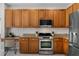 Kitchen featuring stainless appliances, solid wood cabinets, granite counters, and a desk area at 201 Hammock Dunes Pl, Orlando, FL 32828