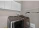 Bright laundry room featuring side-by-side washer and dryer, overhead cabinets, and functional shelving at 201 Hammock Dunes Pl, Orlando, FL 32828
