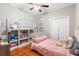 Cozy bedroom featuring wood floors, a ceiling fan, and built-in shelving for storage and display at 2017 W Gore St, Orlando, FL 32805