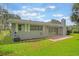 Backyard features a fenced yard, mature trees, sliding glass doors, and brick patio at 2050 Anne Cir, South Daytona, FL 32119