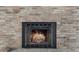Close-up of a cozy brick fireplace with a black metal frame and glowing logs at 2050 Anne Cir, South Daytona, FL 32119