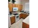 Well-lit kitchen features wooden cabinets, white appliances, and a stainless-steel sink at 223 Palermo St, Davenport, FL 33897