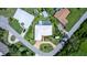 An aerial view of a home with a pool, boat dock, manicured lawn, circular driveway, and lush landscaping at 225 Temple Cir, Eustis, FL 32726