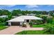 Single-story home with mature landscaping, palm trees, and a long driveway leading to a two-car garage at 225 Temple Cir, Eustis, FL 32726
