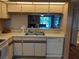 A kitchen sink view through a serving hatch to the living room and sliding glass doors to the outside at 25210 Northlake Dr # 210, Sanford, FL 32773