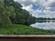 Scenic lake view with lush vegetation, trees and the sky reflecting in the calm water from a wooden deck at 25210 Northlake Dr # 210, Sanford, FL 32773