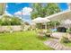 Spacious backyard featuring lush green grass, an umbrella with outdoor seating, and potted plants at 345 Goldstone Pl, Lake Mary, FL 32746