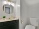 Bathroom with a dark vanity, white counter, and a modern round mirror and toilet at 345 Goldstone Pl, Lake Mary, FL 32746