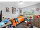 Cozy bedroom with bright orange bedding and plenty of natural light from the window at 3824 Johnson St, Orlando, FL 32805