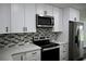 Close-up of kitchen with white cabinets, stainless steel appliances, and mosaic backsplash at 508 Bennett St, Auburndale, FL 33823