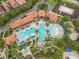 Aerial view of the community pool, with its unique layout, ample seating, and lush tropical landscaping at 5255 Wildwood Way, Davenport, FL 33837