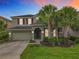 Charming two-story home with a tile roof, well-maintained landscaping, and palm trees at sunset at 5255 Wildwood Way, Davenport, FL 33837