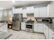 Bright kitchen with stainless steel appliances, granite countertops, and white cabinets, seamlessly connected to living area at 5255 Wildwood Way, Davenport, FL 33837