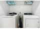Bright laundry room features a white washer and dryer, as well as storage shelves above with towels and an iron at 5255 Wildwood Way, Davenport, FL 33837