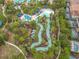 Aerial view shows a winding lazy river, offering a relaxing water feature amid tropical landscaping and seating areas at 5255 Wildwood Way, Davenport, FL 33837