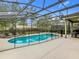 Private backyard oasis featuring a screened-in pool and spa with lush landscaping and plenty of seating at 5255 Wildwood Way, Davenport, FL 33837