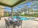 Outdoor dining area overlooking the screened-in pool and spa with a lush backyard at 5255 Wildwood Way, Davenport, FL 33837