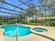 Inviting screened-in pool and spa with lush landscaping, lounge chairs and sunny skies at 5255 Wildwood Way, Davenport, FL 33837