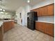 Spacious kitchen with stainless steel refrigerator and wooden cabinets, adjacent to the dining and living areas at 5515 Paradise Cay Cir, Kissimmee, FL 34746