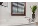 A bathtub with chrome fixtures sits under a window with wood shutters at 602 E Livingston St # 3, Orlando, FL 32803