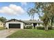 Charming white brick home featuring a black garage door and beautifully landscaped front yard at 7307 Grace Rd, Orlando, FL 32819
