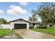 Attractive home showcasing a white brick exterior, black garage door, and well-maintained lawn at 7307 Grace Rd, Orlando, FL 32819