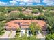 An aerial view showing a community with orange tile roofs surrounded by mature trees, well-manicured lawns and driveways at 8035 Bayside View Dr, Orlando, FL 32819