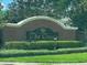 The Green neighborhood entrance sign is framed by a brick structure and manicured hedges at 807 Knightsbridge Cir, Davenport, FL 33896