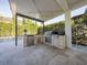 Covered outdoor kitchen with built-in grill, refrigerator, and stone facade at 8085 Ludington Cir, Orlando, FL 32836