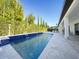 Wide shot of the rectangular pool with blue tile accents, surrounded by green landscaping at 8085 Ludington Cir, Orlando, FL 32836