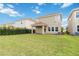 Back exterior view showcasing a manicured lawn and covered brick patio at 8975 Fluffy Lie Ct, Davenport, FL 33896