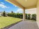 Covered patio with a brick floor overlooking the grassy lawn and manicured landscaping at 8975 Fluffy Lie Ct, Davenport, FL 33896