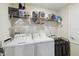 Functional laundry room with a washer, dryer, storage shelf, and a laundry cart for organization at 8975 Fluffy Lie Ct, Davenport, FL 33896