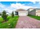 Single-Gathering home featuring an attached two-car garage and a brick-paved driveway with lush green landscaping at 9106 Cut Shot Dr, Winter Garden, FL 34787