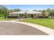 A single-story home on a lush green lawn with mature landscaping, a metal roof, and a paved circular driveway at 920 Grand Ave, Orange City, FL 32763