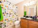 Bathroom featuring wood cabinets with granite counter, a shower-tub combination, and bright lighting at 9539 Silver Buttonwood St, Orlando, FL 32832