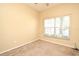 An empty bedroom has neutral carpet, a window with blinds, and light-yellow painted walls at 1086 Wickerwood St, Ocoee, FL 34761