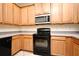 A kitchen featuring natural wood cabinets, black appliances, and gray countertops at 1086 Wickerwood St, Ocoee, FL 34761