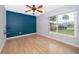 Bright bedroom with wood-look flooring, a ceiling fan, an accent wall, and a large window at 1115 Marni Ridge Ct, Kissimmee, FL 34747