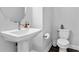Modern half-bathroom features a pedestal sink, toilet, and neutral color palette at 1206 Civitas Way, Winter Garden, FL 34787
